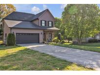Two-story home with a gray garage door, covered front porch, stone accents and a long concrete driveway at 1650 Berkshire Dr, Hickory, NC 28602