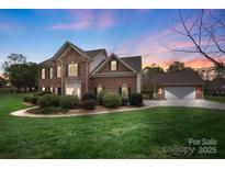Beautiful two-story brick home boasts manicured lawn, mature landscaping, and a detached two-car garage at 301 Prairie Rose Ct, Waxhaw, NC 28173