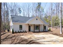Charming exterior featuring a symmetrical facade, covered porch with wooden pillars, and neat landscaping at 676 Chapel Hill Dr, Troy, NC 27371