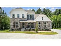 Stunning two-story home featuring a stone facade, rocking chair porch, and beautifully landscaped front yard at 7001 New Town Rd, Waxhaw, NC 28173