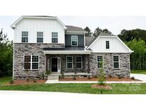 Charming two-story home with stone accents, white siding, a covered porch, and a well-manicured lawn at 7001 New Town Rd, Waxhaw, NC 28173