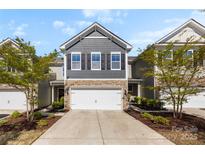 Charming townhome featuring stone accents, gray siding, a two-car garage, and manicured landscaping at 1212 Croft Dr, Fort Mill, SC 29708