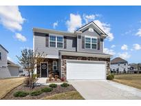 Charming two-story home features gray siding, stone accents, a two-car garage and a welcoming front door at 15122 Lake Ridge Rd, Charlotte, NC 28278