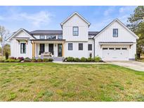 Charming two-story modern farmhouse exterior with black trimmed windows and attached two-car garage at 211 Killian Rd, Stanley, NC 28164