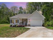 Charming single-story home featuring a welcoming front porch and a well-maintained front yard with an attached garage at 2402 Winfield St, Kannapolis, NC 28083