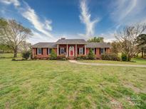 Charming single-story brick home with a well-manicured lawn and mature trees under a bright blue sky at 24436 Nc 24/27 Hwy, Albemarle, NC 28001