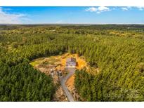 Expansive aerial view of a metal building surrounded by dense forest, with a gravel driveway and several parked vehicles at 2710 Wyatt Grove Church Rd, Richfield, NC 28137