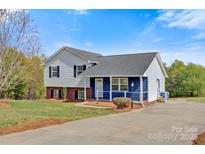 Charming two-story home featuring gray and blue siding, black shutters, and a well-maintained front yard with mature trees at 2948 Christy Leigh Dr, Newton, NC 28658