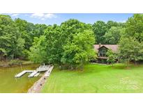 Lakefront home featuring a private dock, lush greenery, and well-maintained lawn at 307 Stillwater Rd, Troutman, NC 28166