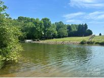Scenic lake view with lush greenery, a dock, and clear blue skies, perfect for serene living and outdoor activities at 307 Stillwater Rd, Troutman, NC 28166