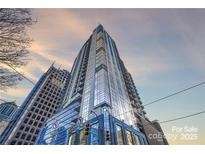 Striking high-rise condo building with floor-to-ceiling windows against a dramatic sunset sky at 333 W Trade St # 1802, Charlotte, NC 28202