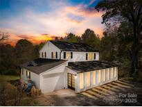 Charming two-story home with a white exterior, black shutters, and well-manicured landscaping at sunset at 4375 Creek Ave, Midland, NC 28107