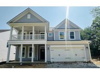Charming two-story home with a covered porch, attached garage, and light gray siding at 5100 Verona Rd # 96, Charlotte, NC 28213