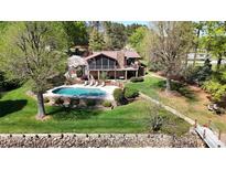 An aerial view of a beautiful stone home with a sparkling pool and a lush green lawn at 7424 Windy Pine Cir, Denver, NC 28037
