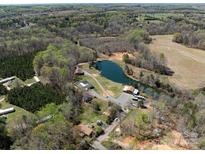Stunning aerial view of property with a private lake and surrounding lush greenery and multiple outbuildings at 7545 Brancy St, Kannapolis, NC 28081