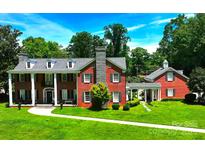 Stately red brick home with a stone chimney, well-manicured lawn, and an attached guest house at 1035 Pee Dee Ave, Albemarle, NC 28001