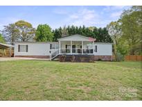 Charming single-story home featuring a welcoming front porch and well-manicured lawn and carport at 115 Oak Creek Rd, Statesville, NC 28625
