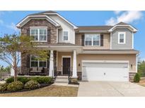 Charming two-story home with stone accents, covered porch and manicured landscaping at 116 Rainbow Trout Trl, Fort Mill, SC 29715