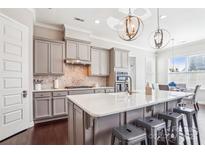 Beautiful kitchen boasts gray cabinets, quartz countertops, stainless steel appliances, and a central island at 15402 Country Lake Dr, Pineville, NC 28134