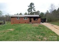Exterior view of a single-story brick home featuring a metal roof and a spacious front yard at 1842 Quail Run Dr, Kingstown, NC 28150