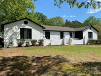 Charming, painted brick home featuring black trim, well-maintained landscaping, and inviting curb appeal on a sunny day at 1946 Fairway Dr, Lancaster, SC 29720