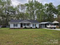 Charming single-story home with a well-maintained lawn and a covered parking area in the backyard at 2021 Hilton Way Rd, Lancaster, SC 29720