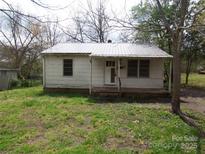 Modest single-story home featuring metal roof and mature trees in front yard at 605 W Elm St, Shelby, NC 28150