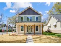 Charming two-story home featuring a covered front porch with wooden columns and a light green front door at 68 Cabarrus W Ave, Concord, NC 28025