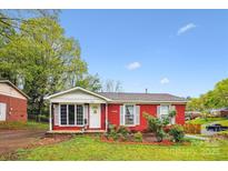Charming red brick home with a cozy front porch and well-manicured lawn at 6800 Deanwood Pl, Charlotte, NC 28217