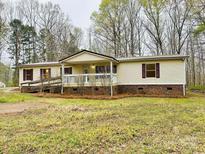 Inviting single-story home with a charming front porch and convenient ramp access surrounded by lush greenery at 1031 Lester Trl, Iron Station, NC 28080