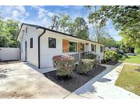 Charming single-story home with white siding, black trim, a well-manicured lawn and beautiful plantings at 2038 Sandhurst Dr, Charlotte, NC 28205
