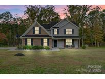 Charming two-story home featuring a brick facade and gray siding surrounded by a lush, landscaped yard at 3018 Corinth Church Rd, Monroe, NC 28112