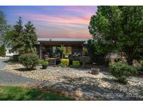 Charming log cabin home boasts a covered porch and well-maintained landscaping at 4478 Fork Rd, Norwood, NC 28128