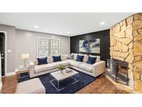 Cozy living room with stone fireplace, dark accent wall, neutral colored sectional, and stylish decor at 485 Camrose Ne Cir, Concord, NC 28025