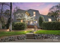 Contemporary home featuring a landscaped front yard, stone accents, and blooming tree, enhanced by outdoor lighting at 6147 Lake Providence Ln, Charlotte, NC 28277
