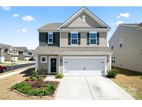 Charming two-story home features a two-car garage, and welcoming curb appeal with a manicured lawn and garden at 7742 Sea Turtle Way, Indian Land, SC 29720