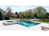 A gorgeous pool with a water feature and hot tub overlooking a pond is perfect for relaxing and entertaining guests at 819 Beauhaven Ln, Waxhaw, NC 28173