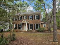 Charming two-story brick home featuring black shutters, a white door, and a well-maintained front yard with mature trees at 8813 Golf Ridge Dr, Charlotte, NC 28277
