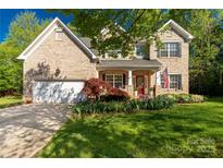 Charming brick home with manicured lawn, flowering plants, and a welcoming red front door at 206 Coburn Ct, Fort Mill, SC 29715
