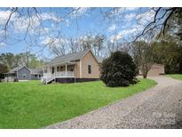 Charming home with a welcoming front porch, lush lawn, and gravel driveway at 308 Birch St, Lowell, NC 28098
