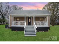 Charming home featuring a welcoming front porch with decorative railings and a well-maintained lawn at 308 Birch St, Lowell, NC 28098