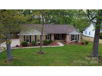 Charming brick home with blue shutters, mature landscaping, and a well-manicured lawn at 413 Parallel Dr, Harrisburg, NC 28075