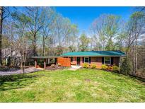 Charming single-story brick home with a green metal roof, carport, and a well-manicured lawn at 444 27Th Avenue Nw Cir, Hickory, NC 28601