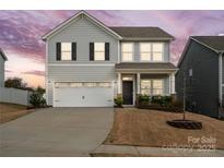 Charming two-story home featuring gray siding, a two-car garage, and a manicured front yard at twilight at 5104 Thomasville Dr, Belmont, NC 28012