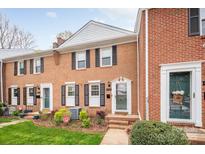 Charming brick townhome featuring black shutters, a landscaped yard, and a welcoming front entrance at 8308 Knights Bridge Rd, Charlotte, NC 28210