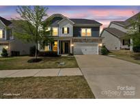 Charming two-story home featuring stone accents, a two-car garage, manicured lawn, and covered porch entry at 15126 Shallow Ridge Rd, Charlotte, NC 28278