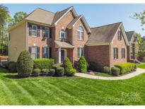 Stunning brick home featuring manicured landscaping, lush green lawn, and classic architectural design at 202 Weeping Spring Dr, Mooresville, NC 28115