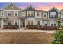 Charming townhome featuring diverse siding and brick accents against a backdrop of a beautiful sunset at 9654 Old Garden Cir, Gastonia, NC 28056