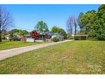 Charming single-story home with a well-manicured lawn, carport, and a welcoming driveway at 140 Oak Ave, Mount Holly, NC 28120