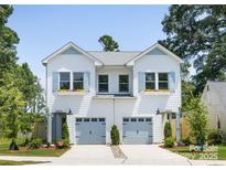 Charming two-story duplex featuring white siding, light blue shutters, flower boxes, and individual garage doors at 2003 Ashley Rd # A, Charlotte, NC 28208